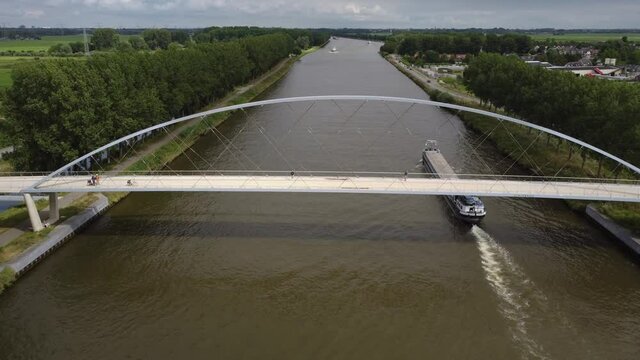 Pedestrian and cyclist bridge over the Amsterdams Rijn Canal,  waterway in Nigtevecht The Netherlands. Liniebrug. Big ship.