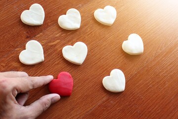 Obraz premium Hand pick up red heart over white heart. Searching for love, looking for real love, valentine's day concept