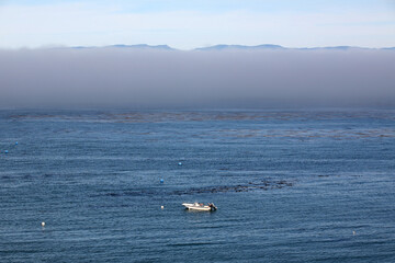 Small boat on the sea and clouds of fog