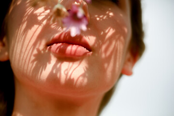 lips of a beautiful girl with shadow from wildflowers. Summer autumn concept