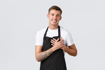 Small business owners, coffee shop and staff concept. Happy handsome blond guy in black apron,...