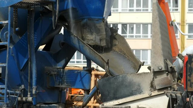 Repair and maintenance of construction equipment on the building site. Washing the troughts of the concrete mixer with water on construction site, closeup view.