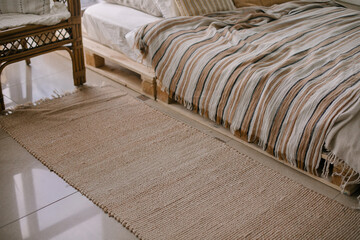 Brown handmade knitted bedside rug in bedroom in scandinavian style