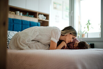 Obraz premium Cute little girl is playing with her mother in the bedroom.