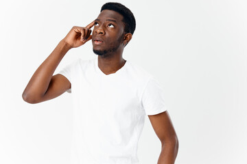 interested young man of african appearance in white t-shirt touches his head 