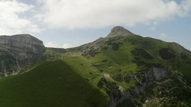 Aerial drone footage of a mountain ridge in sunny weather with the clouds casting moving shadows. In the Alps of Trentino Alto Adige, Italy - Monte Bondone