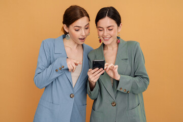 Young two women using and pointing finger at mobile phone