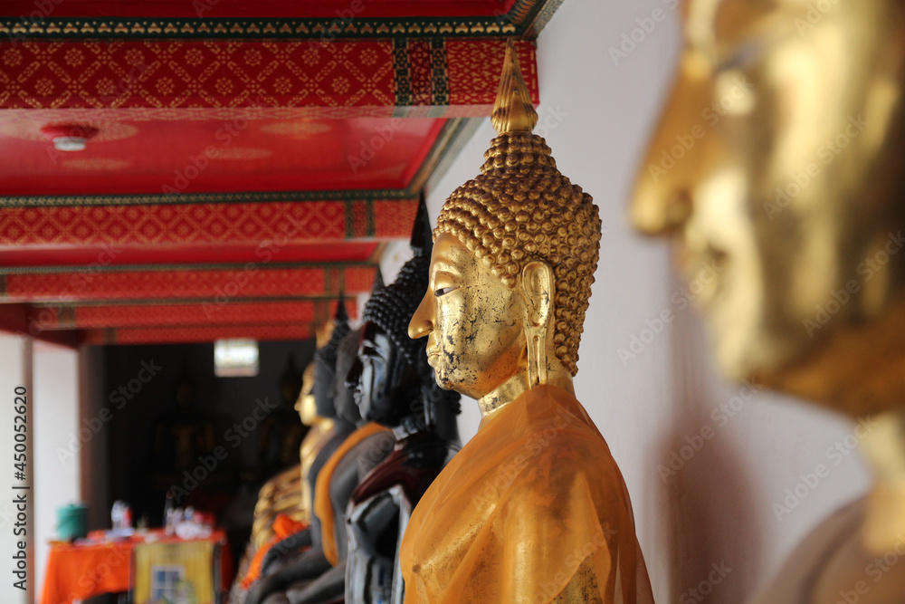 Poster closeup of black and golden buddha statues in wat pho, thailand