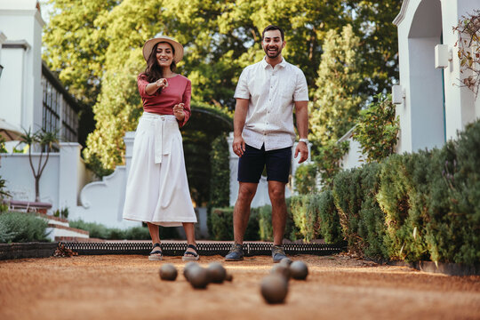 Happy tourist couple playing petanque together