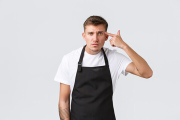 Employees, grocery stores and coffee shop concept. Annoyed and concerned barista, cafe manager scolding waiter for making stupid mistake, point at temple, accusing someone crazy