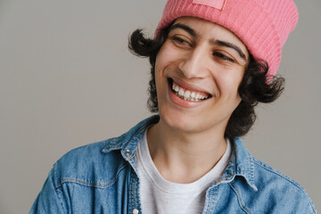 Young brunette man in pink hat laughing and looking aside