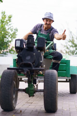 Fototapeta premium Satisfied farmer portrait sitting behind the wheel of a two-wheeled tractor.