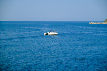 White catamaran in the blue sea with a strip of shore