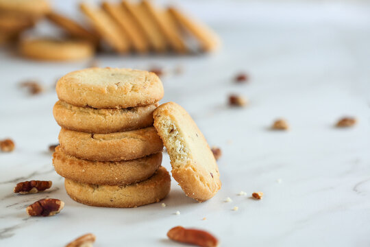 Stack of pecan sandies cookies with one missing a bite. Selective focus with blurred foreground and background.