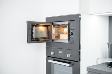 Microwave with open door and food inside. Modern kitchen appliances