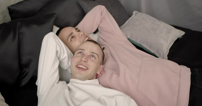 Happy gay couple lying on bed at home