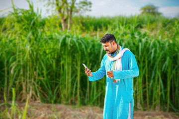 Young indian farmer talking on mobile phone at sugarcane field, talking on phone and laughing too...