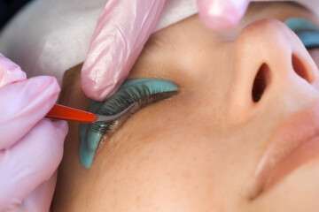 Cosmetologist bending lashes with needle into curlers, lift eyelashes laminaton procedure in beauty salon for woman, closeup face. Beautician making lash lifting in cosmetology clinic, hands closeup.