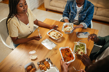 Young happy friends having fun during lunchtime at home