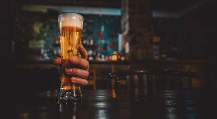 man holds a glass of beer in his hand at the bar or pub