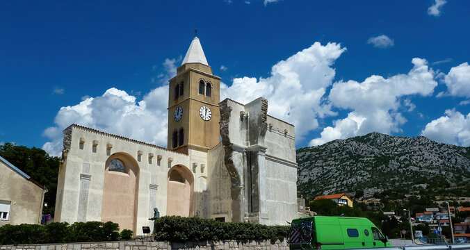 Karlobag, Croatia - May 9. 2017: View on old partly ruin church with mountain against blue summer sky with cumulus clouds
