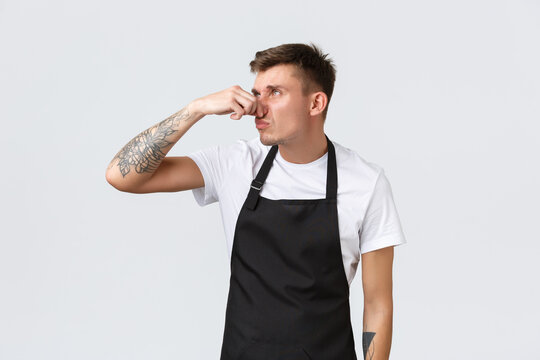 Employees, Grocery Stores And Coffee Shop Concept. Annoyed And Tired Funny Barista, Cafe Staff Hates Taking Out Stinky Trash, Shut Nose And Roll Eyes Displeased From Disgusting Smell