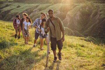 Group of friends, young men and women walking, strolling together during picnic in summer forest, meadow. Lifestyle, friendship,