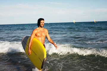  Portrait of handsome surfer with his surfboard. Young man with a surfboard on the beach