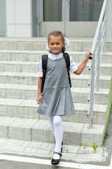 a schoolgirl girl on a school background with a backpack, smiling, with long hair, in a school uniform is going to study as an excellent student at the beginning of the school year. September 1