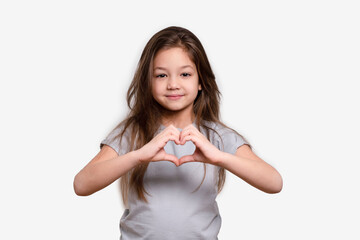 Friendship. Happy childhood concept, smiling. Little girl in white or grey blank t-shirts showing heart with hands. Hand love. Love symbol.