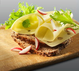 Emmentalerbrot mit Salat und Radieschen auf Holzbrett als Freisteller