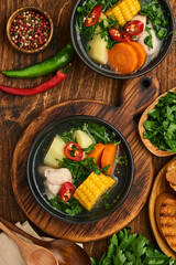 Chilean meat soup with pampkin, corn, fresh coriander and potatoes on old wooden table background. Cazuela. Latinamerican food.