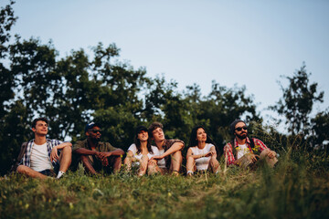 Meet sunset. Group of friends, young men and women walking, strolling together in summer forest,...