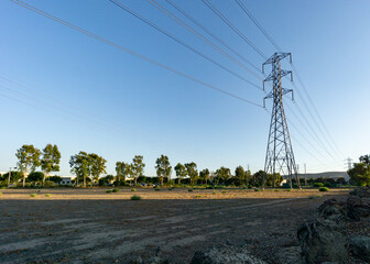 High voltage tower on blue sky with empty field