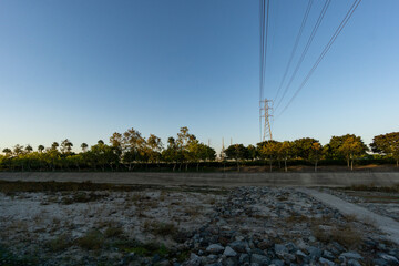 High voltage tower on blue sky with empty field
