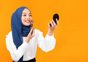 Beauty muslim woman with hijab applying makeup brush. Girl gets blush on the cheekbones.