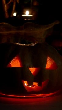 Home decoration with spooky glows halloween pumpkin head Jack Lantern face and burning candle. Carved eyes, mouth. Vertical video. Traditional Halloween symbol.
