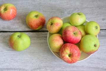 garden apples on white plate on grey wooden background