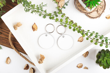 From above modern keychain mock ups near green plants and dried leaves on white background. Key chain mock up