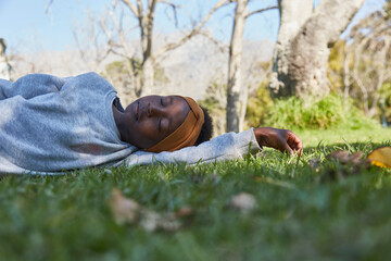 Pretty young black girl lying on grass in grey tracksuit.