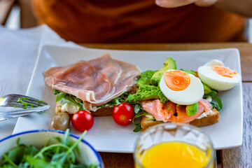 Man eating breakfast toast with egg.Toast for breakfast.Breakfast in the hotel.Home cooked healthy food.Toast for breakfast.Toast with avocado, arugula and ham.Avocado toast.Lunch at work.Breakfast 