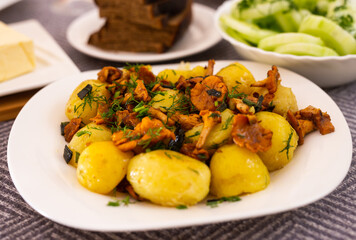 baked  potatoes with chanterelles, served with herbs on white plate
