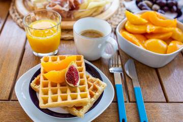 breakfast with coffee.Waffles for breakfast with jam and fruit.Homemade waffles with berries in a plate on a wooden table.Belgian waffles on a white plate.Belgian waffles with peaches and figs.tasty 