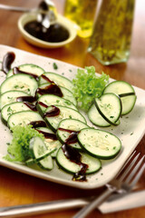 travessa com salada de pepino e alface com molho oriental sobre fundo de madeira