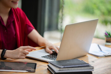 Fototapeta premium A beautiful woman in a red dress is enjoying working with her credit card on her laptop computer.