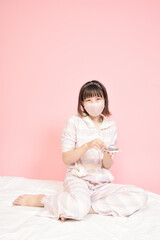 Fototapeta premium マスクを着けてスマホを見る若い女性