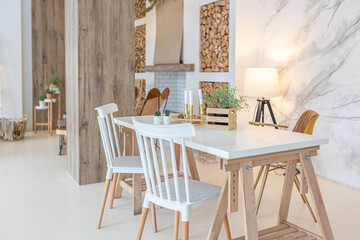 Fashionable modern interior of a light studio apartment with wooden columns in the loft style, decorated with brick, marble and wood with stylish furniture and white walls