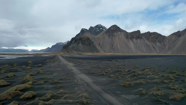 Iceland Drone of Vestrahorn Stoksness Black Sand Beach with long lonely Dirt Road