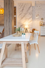 Fashionable modern interior of a light studio apartment with wooden columns in the loft style, decorated with brick, marble and wood with stylish furniture and white walls