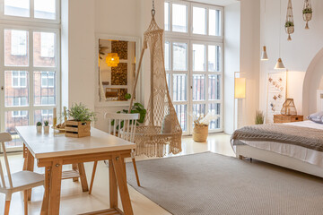 Fashionable modern interior of a light studio apartment with wooden columns in the loft style, decorated with brick, marble and wood with stylish furniture and white walls